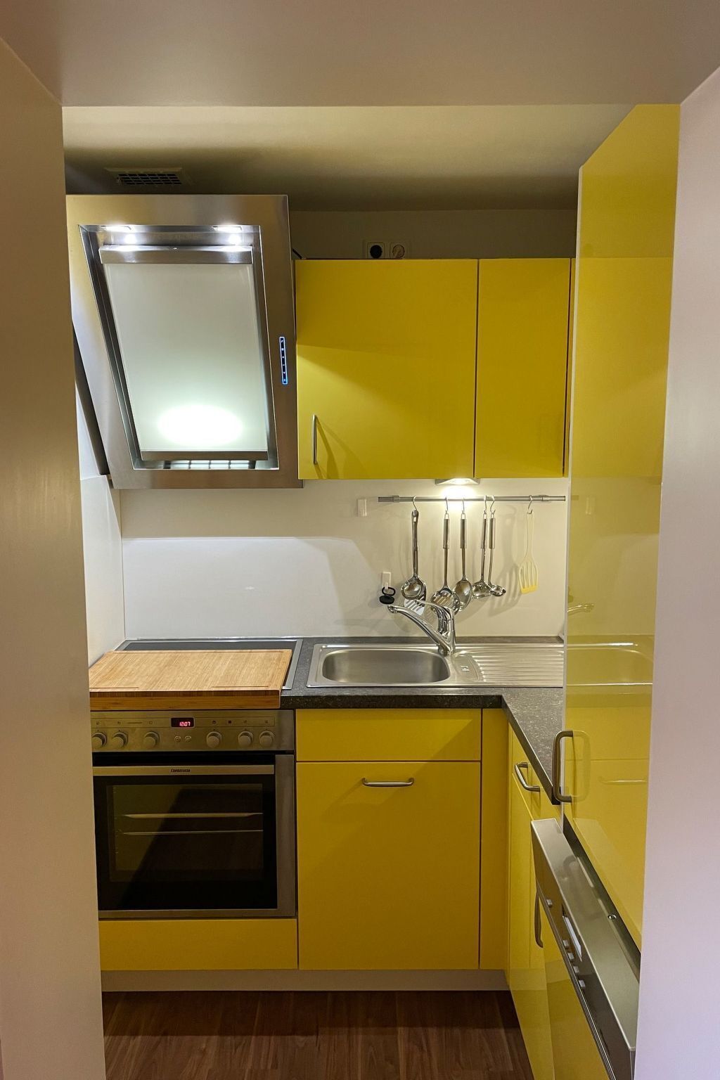 A compact kitchen with yellow cabinets, a stainless steel sink, a built-in oven, and a microwave.