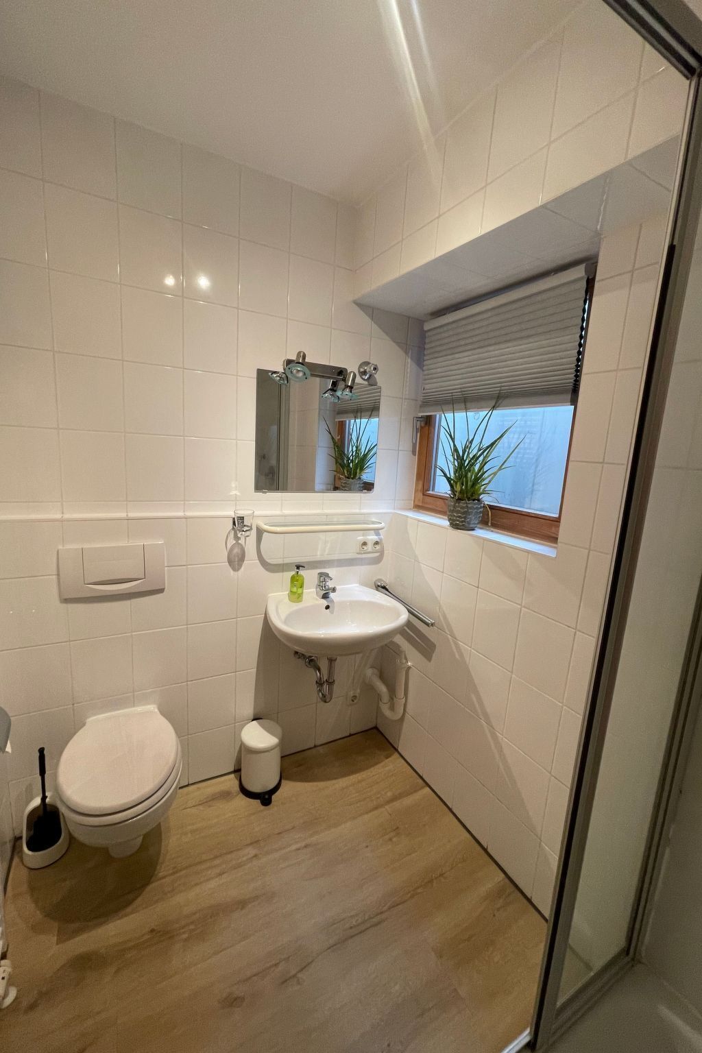 A bathroom with a toilet, sink, and a window with a view.