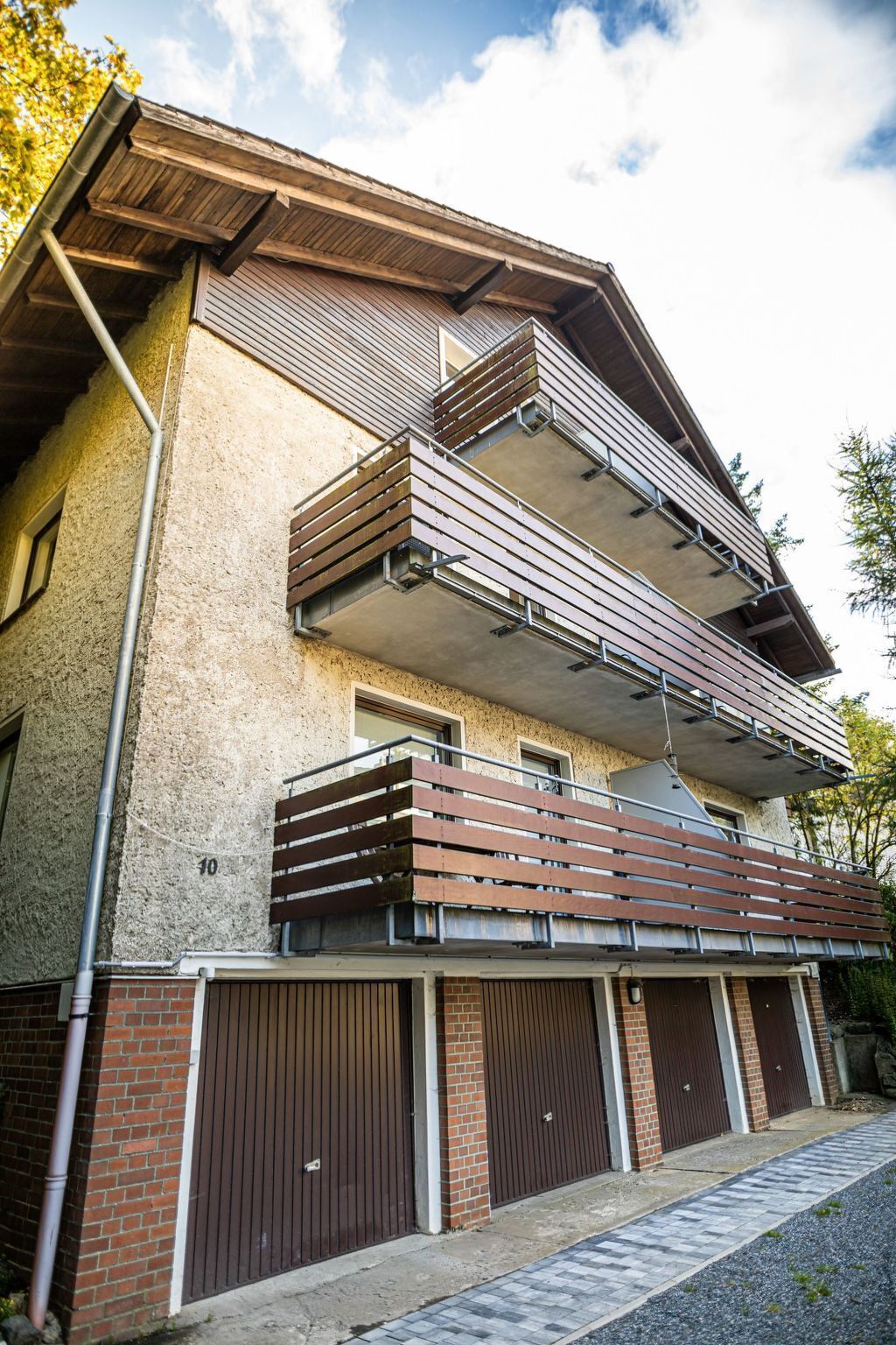 Een meerlaags gebouw met een balkon op de tweede verdieping, een bakstenen gevel en een garage met vier deuren.