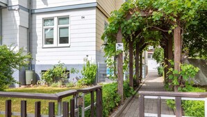 Un chemin menant à un bâtiment portant le numéro 54, avec une clôture en bois et de la verdure.