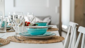 A dining table set with blue bowls, clear glasses, and woven placemats.