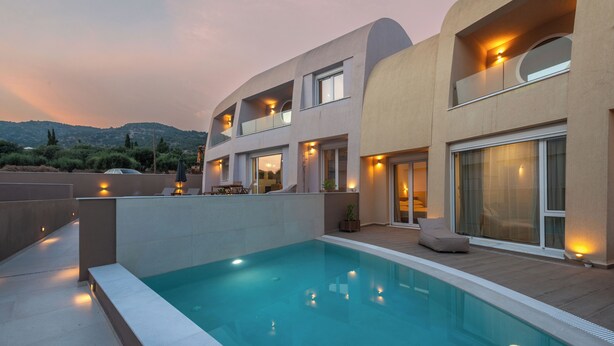 A modern house with a swimming pool, balconies, and outdoor lighting.