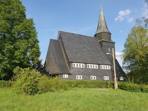 Eine Kirche mit steilem Dach und einem hohen Kirchturm.