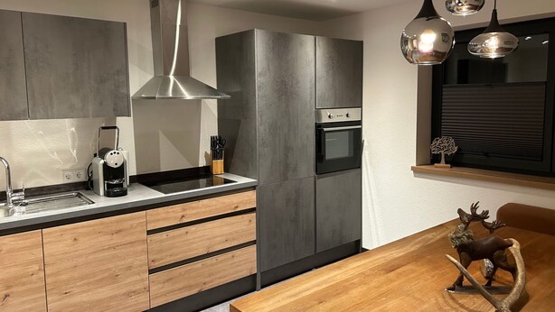 Eine moderne Küche mit Einbauofen, einer Kaffeemaschine und einem Holzesstisch mit einer Hirschskulptur.
