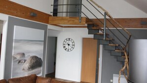 Un loft moderne avec un escalier en bois, une grande horloge et une vue sur l’extérieur.