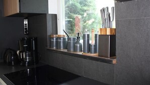 Une cuisine moderne équipée d’une cuisinière intégrée, d’une machine à café et de différents récipients de rangement placés sur le plan de travail.