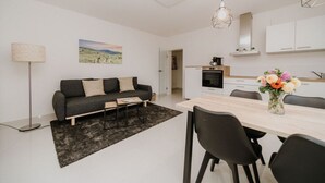 Ein moderner, gut beleuchteter Wohnbereich mit Sofa, Couchtisch und Esstisch.