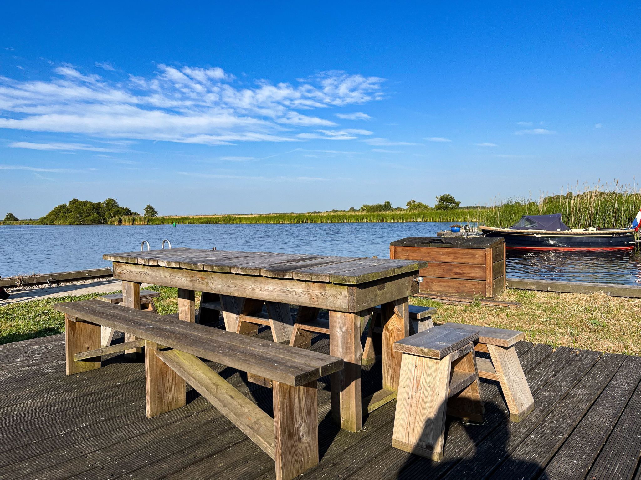 Eine Holzstege mit Picknicktischen und einem Boot.