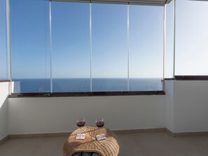 A balcony with a clear view of the sea, a small table with two glasses of red wine, and a woven pouf. - Helle Wohnung mit atemberaubender Aussicht auf das Meer und den Strand by Interhome (Radazul)