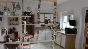 Une cuisine moderne avec des meubles blancs, un plan de travail en bois et un coin repas comprenant des chaises et une table, le tout dans des tons blancs.