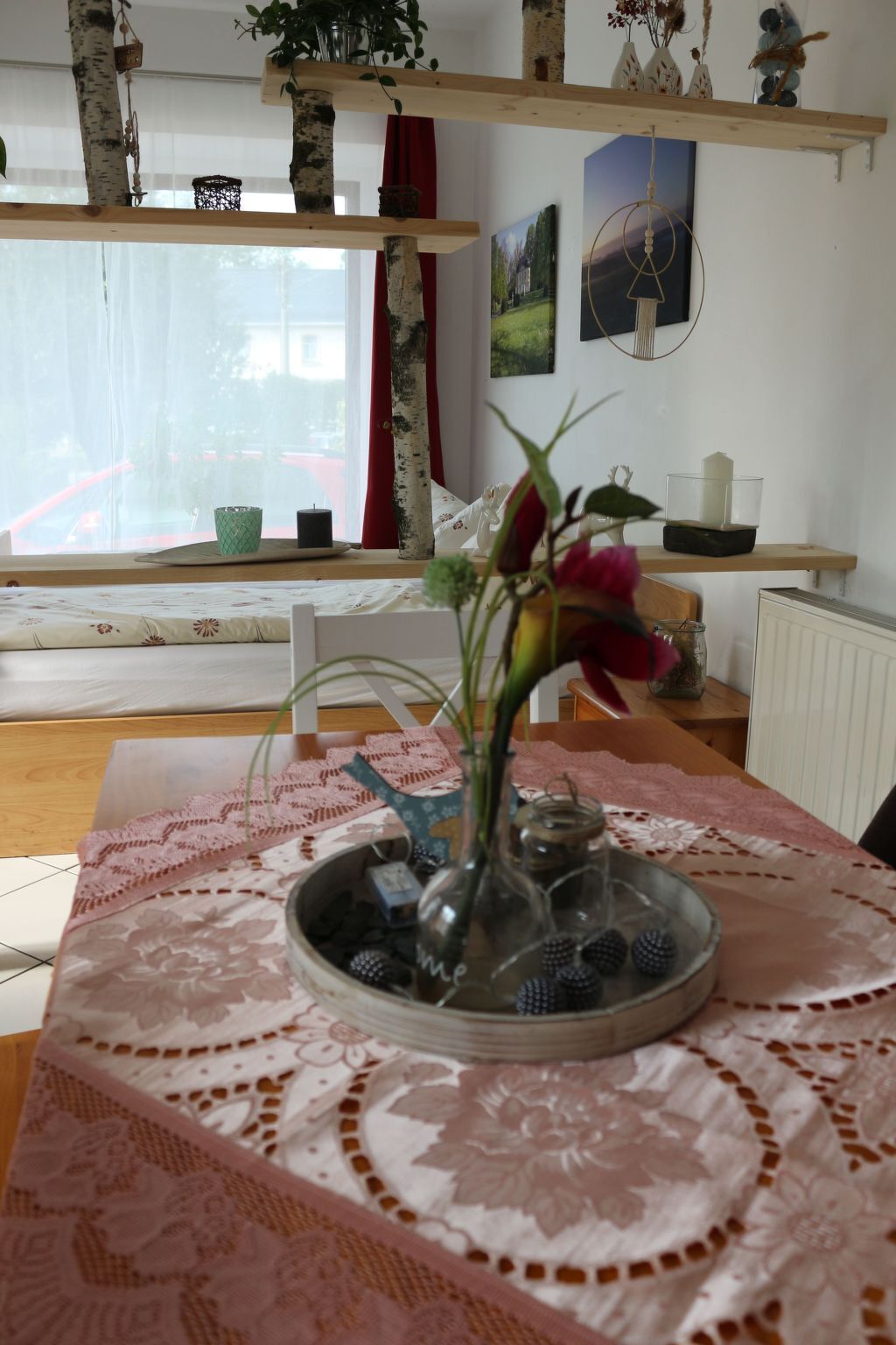 A room with a wooden table, a vase with flowers, and a window with curtains.