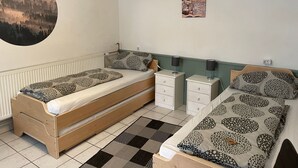 A bedroom with two beds, a radiator, a wall clock, and a motivational poster. - Appartement Wasserfall by Interhome (Stall)