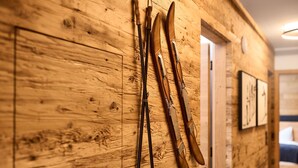 Eine Holzwand mit lehnenden Skiern und Stocken.