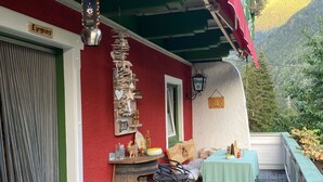 Mukava ulkoalue, jossa on pöytä ja tuoleja, puutynnyri ja kyltti, jossa lukee ”Eingang” (sisäänkäynti).
