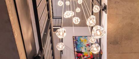 A staircase with a modern design, featuring a metal railing and a series of hanging pendant lights.