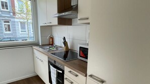 Une cuisine moderne avec des armoires blanches, un plan de travail en bois et une fenêtre donnant sur l’extérieur.