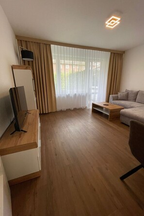 A modern living room with a flat-screen TV, a sofa, and a coffee table. - Kernsanierte Ferienwohnung in ruhiger und zentraler Lage by Interhome (Wilhelmshaven)