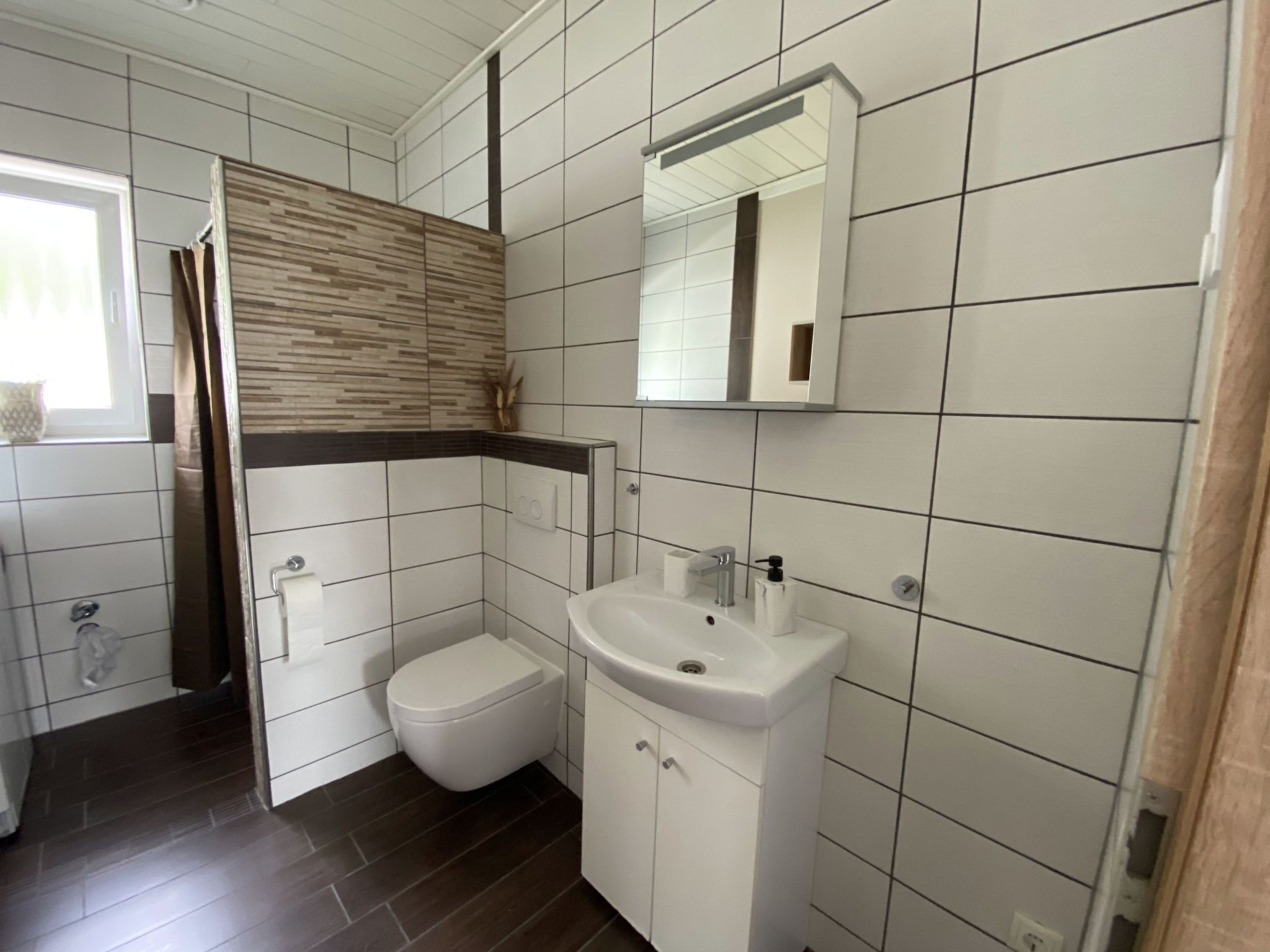 Et moderne badeværelse med toilet, vask og spejl.