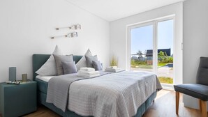 A modern bedroom with a bed, bedside tables, and a view of the outdoors. - Maltes-Ostseekoje by Interhome (Hasselberg)