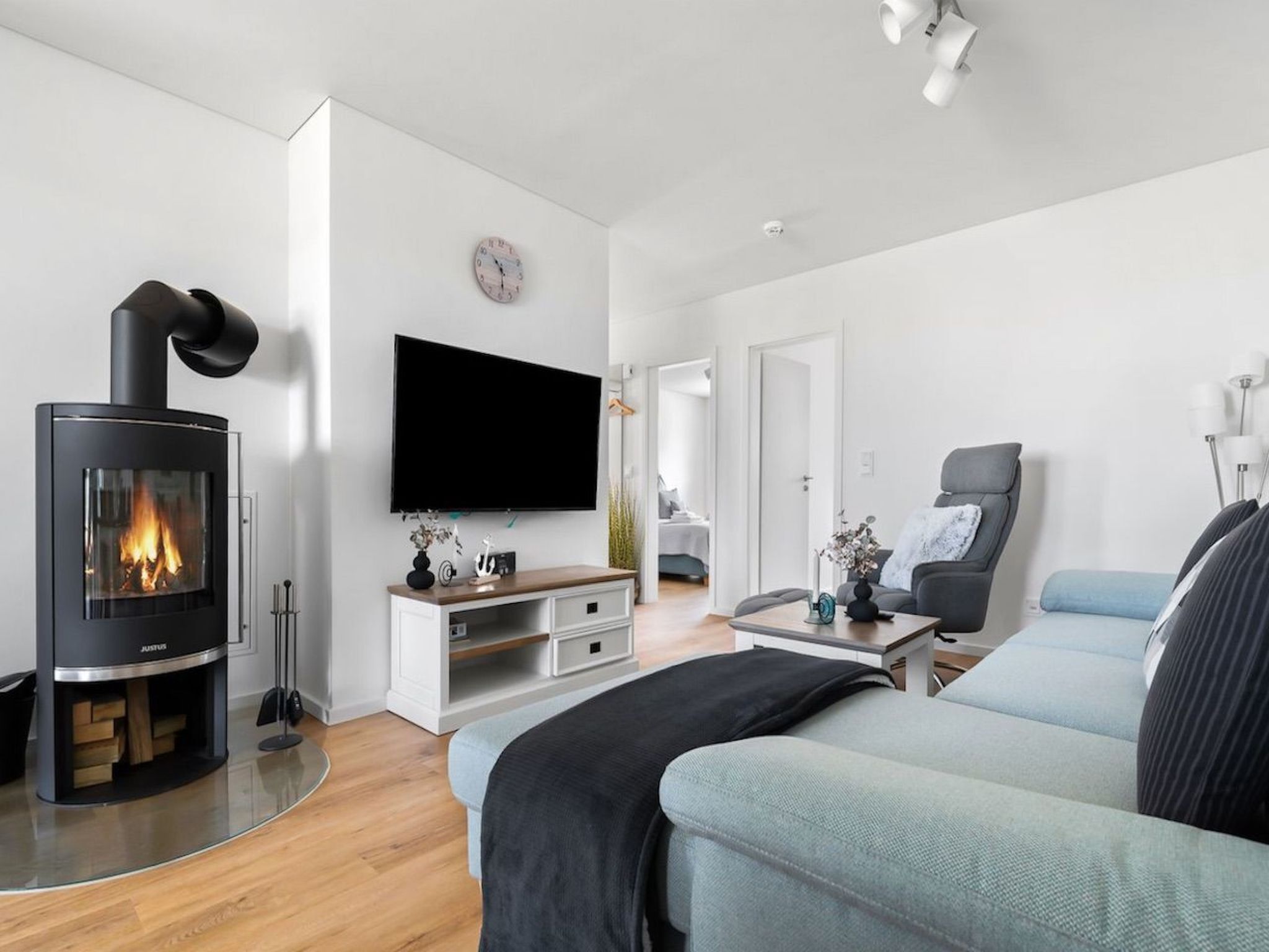 A modern living room with a wood-burning stove, a flat-screen TV, and a comfortable seating area.