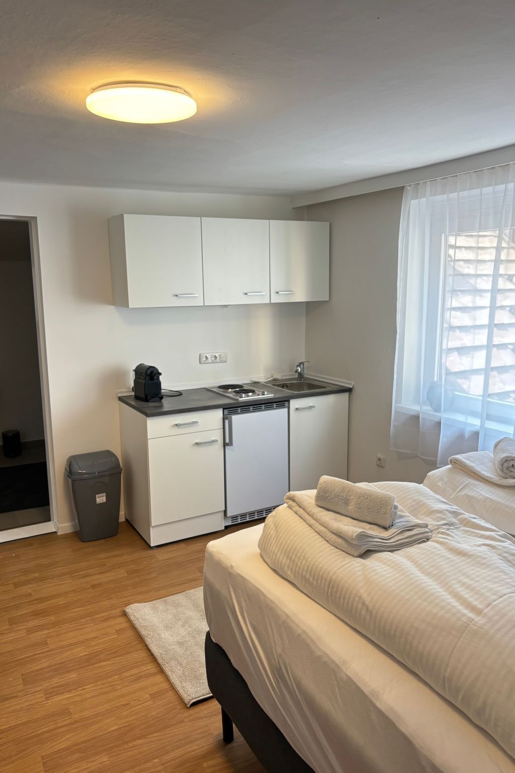 Une chambre compacte comprenant un lit, une petite kitchenette et une salle de bain.