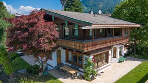 A two-story wooden house with a balcony, a patio with outdoor furniture, and a view of a mountain. - Villa Emma, Ferienhaus für bis zu 10 Personen, eigener Garten, absolute Privats by Interhome (Kaltenbach)