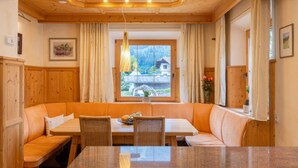 A cozy dining area with a wooden ceiling, a large window with curtains, and a view of a house. - Villa Emma, Ferienhaus für bis zu 10 Personen, eigener Garten, absolute Privats by Interhome (Kaltenbach)