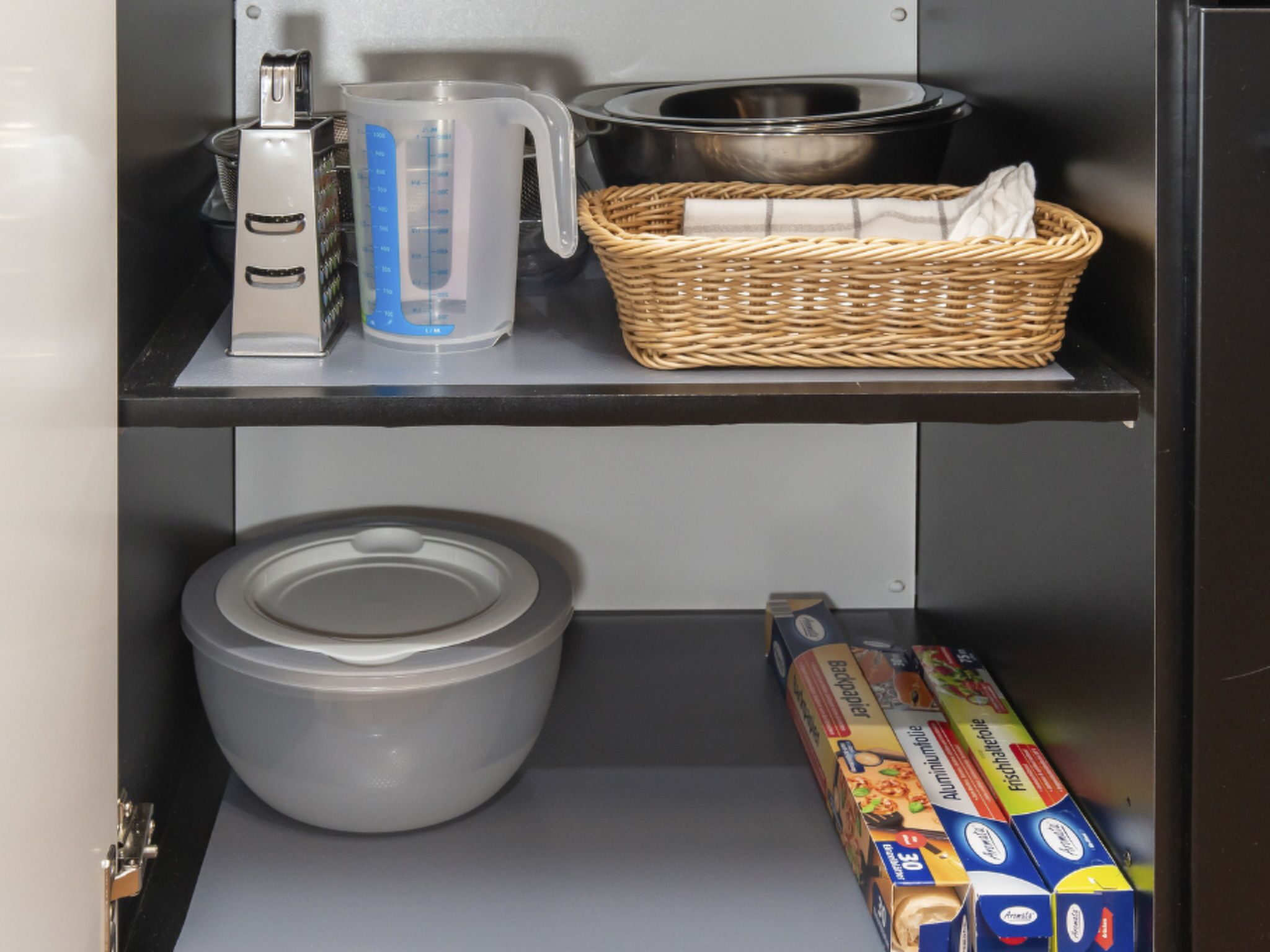 A kitchen with a kettle, measuring jug, and a basket on the countertop.