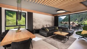 Una sala de estar moderna con techo de madera, ventanas amplias, un sofá, una mesa de centro y un comedor con sillas y una mesa de madera.