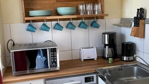Eine kleine Küche mit Mikrowelle, Toaster, Kaffeemaschine und Geschirrspüler.