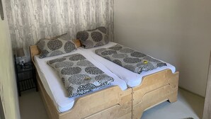 Ein Einzelbett mit Holzrahmen, zwei Kissen mit Punkten und ein Nachttisch mit Lampe.
