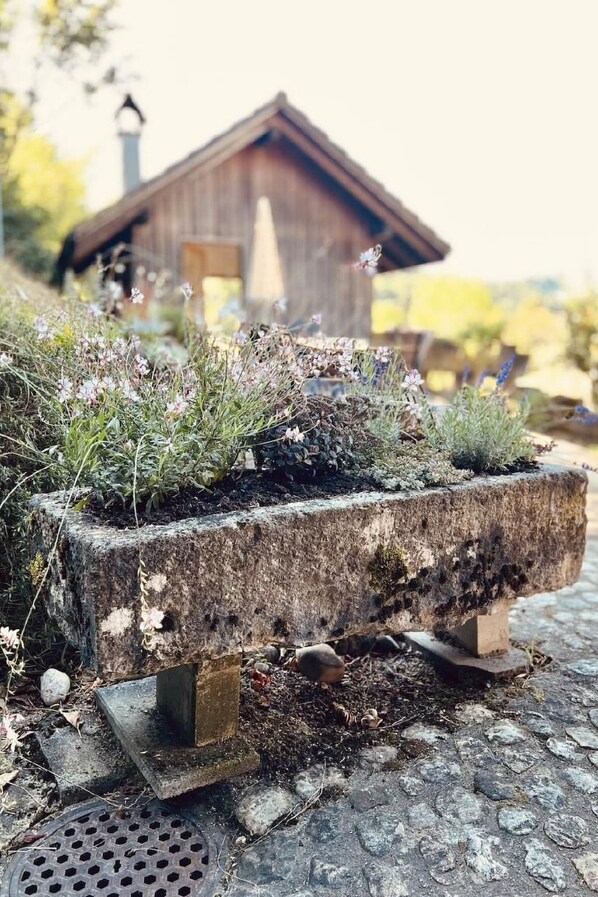 A rustic stone planter with wildflowers and a wooden cabin in the background.