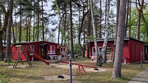A campsite with red cabins, a playground, and a paved path. - Ferienanlage Am Sidowsee by Interhome (Fürstenberg)