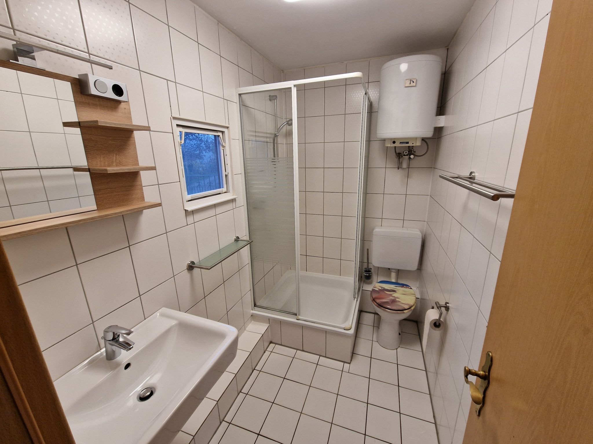 Een badkamer met een wastafel, toilet, douche en een raam met uitzicht.
