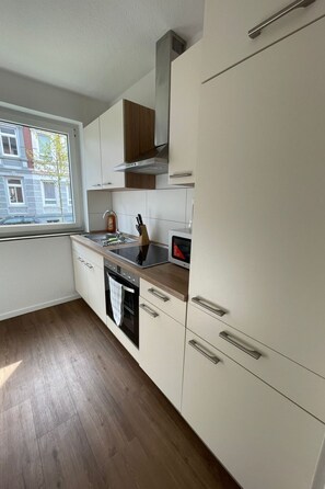 A modern kitchen with white cabinets, a wooden countertop, and a window providing a view of the outside. - Kernsanierte Ferienwohnung in ruhiger und zentraler Lage by Interhome (Wilhelmshaven)