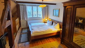Um quarto aconchegante com uma cama de madeira, uma mesa de cabeceira com abajur e uma janela com cortinas.