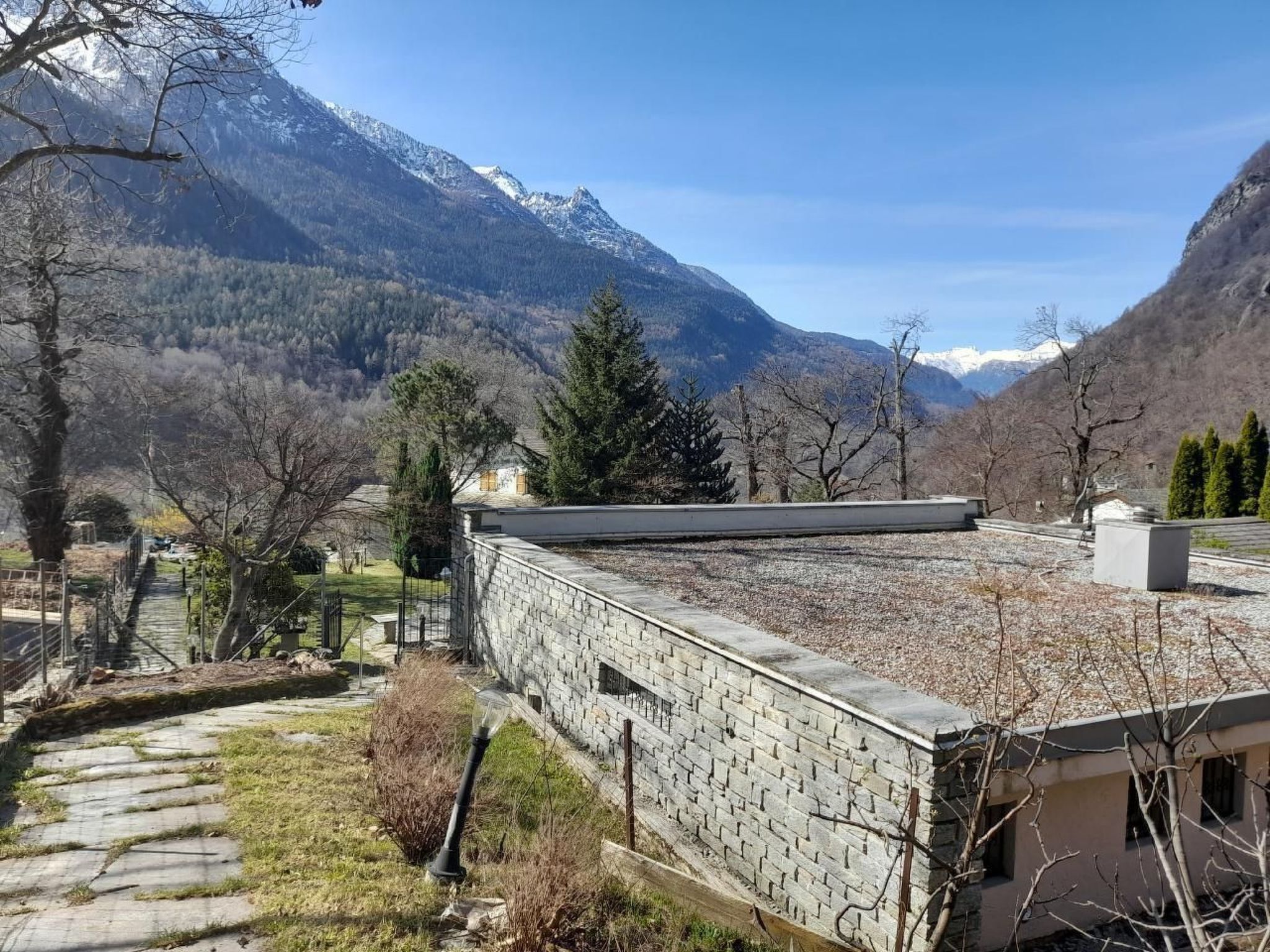 Ein Gebäude aus Stein mit flachem Dach, umgeben von einer gebirgigen Landschaft und spärlicher Vegetation.