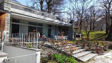 A modern house with a stone facade, large windows, and a patio area with outdoor furniture.