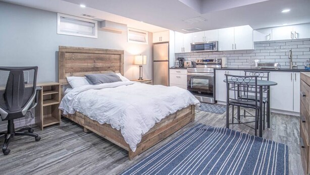 Un dormitorio moderno con una cama de madera, un escritorio y una kitchenette.