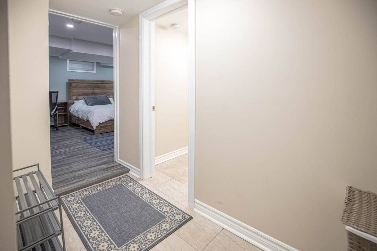 Un corridoio che conduce a una camera da letto con un letto a letto in legno, un piccolo angolo salotto e una porta che dà su un'altra stanza.