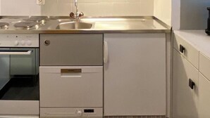 A modern kitchen with white cabinetry, a stainless steel sink, and a built-in oven. - Derby 37 by Interhome (St. Moritz)