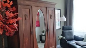 A living room with a wooden cabinet, a mirror, a potted plant, a sofa, and a rug. - in Wernigerode mit Grill und Garten by Interhome (Wernigerode)