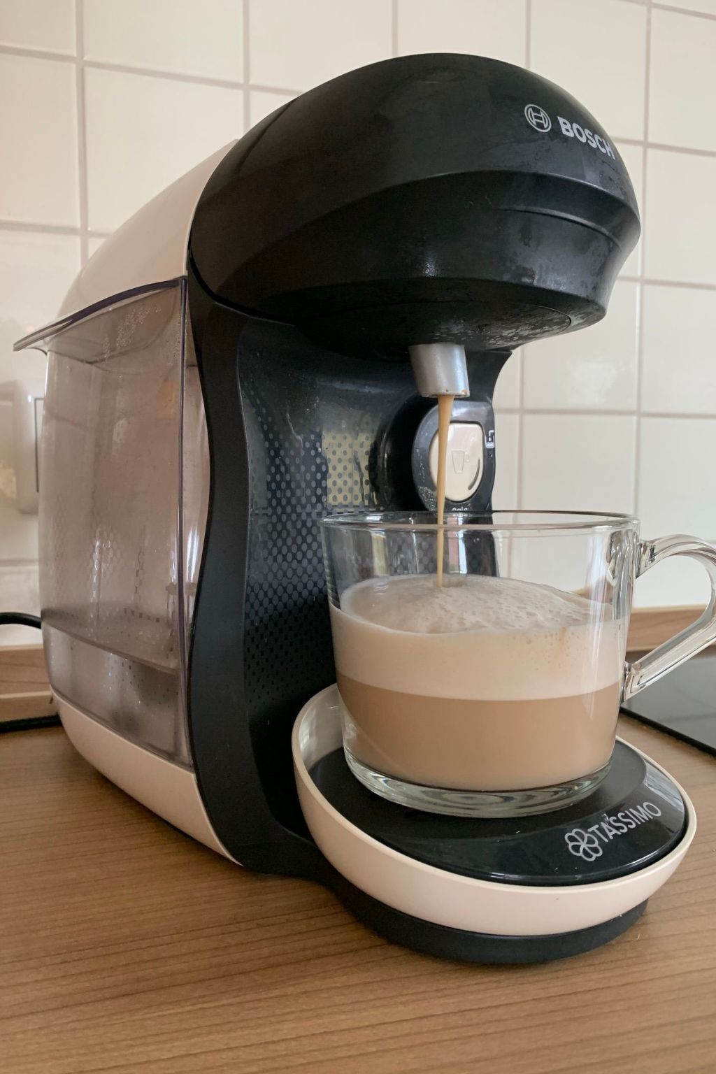 Una cafetera con una taza de vidrio sobre su base.
