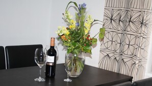 Ein Esstisch mit zwei Weingläsern, einer Weinflasche und einer Blumenvase.