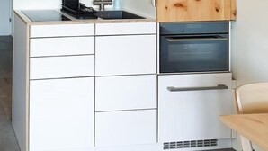 A kitchen with wooden cabinets, a sink, and a stove. - Rosatsch B15 - Champfèr by Interhome (St. Moritz)