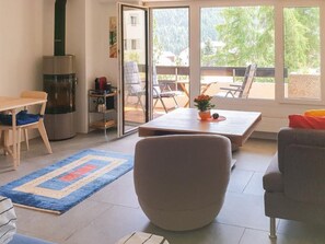 Ein modernes Wohnzimmer mit einer Couch, einem Couchtisch und einem Essbereich mit Tisch und Stühlen. Eine Schiebetür aus Glas führt zu einer Außenpatio-Terrasse.