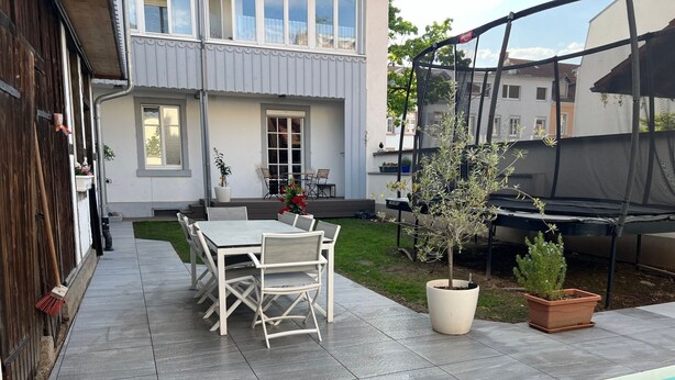 Eine Terrasse mit Pool, einem Esstisch mit Stühlen und Topfpflanzen.