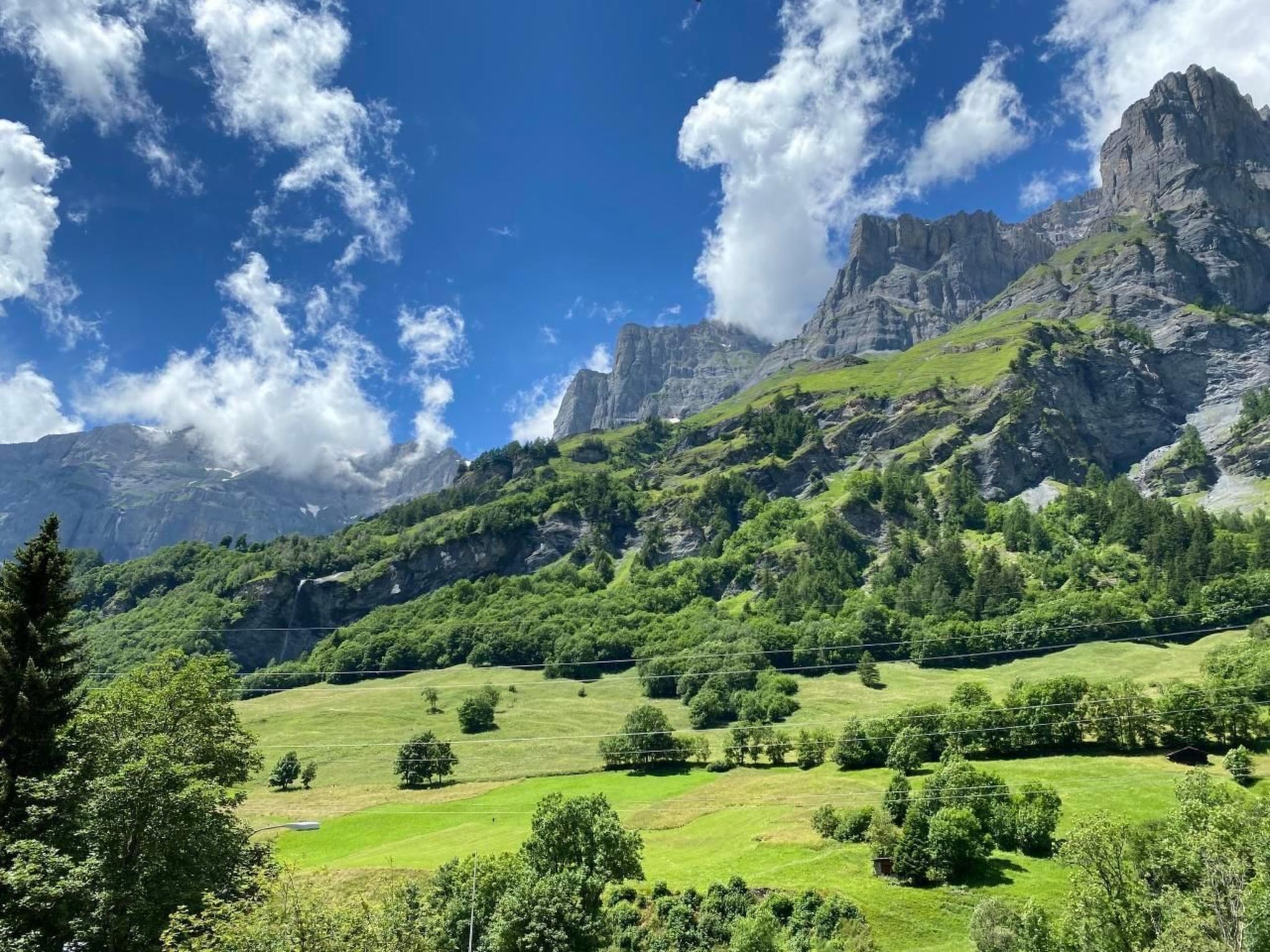Un paisaje montañoso con campos verdes y acantilados rocosos.