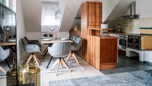 A modern kitchen with a built-in oven and a dining area with a wooden table and grey chairs. - dasWeinbergblick - Landhaus dasThomas by Interhome (Henndorf im Burgenland)