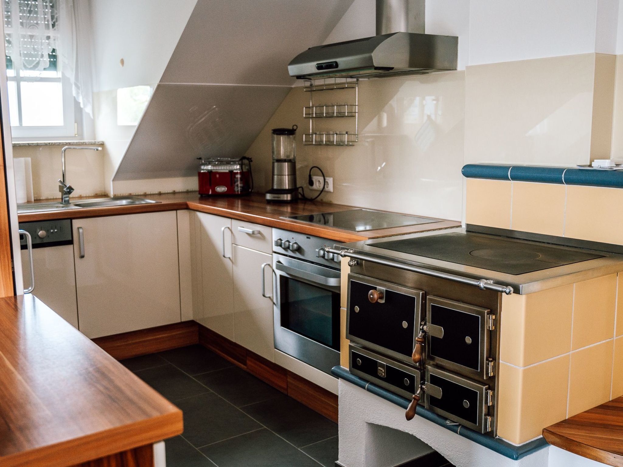 Cozinha compacta com fogão, forno e cafeteira.